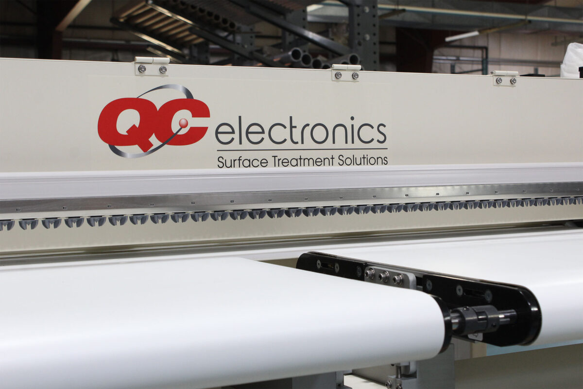 close up of sheet corona treater with static bar and conveyer system by QC Electronics